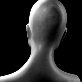 A back view of a mannequin highlights its smooth, featureless contours. The minimalist design