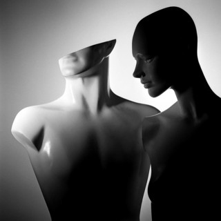 Two stylized mannequins stand closely together, featuring smooth surfaces and abstract shapes.