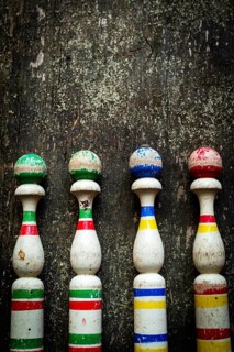 Vibrant wooden bowling pins stand aligned against a weathered surface, inviting players to enjoy a