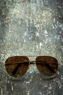 Vintage sunglasses rest on a weathered wooden surface, basking in gentle natural light. The scene