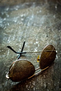 A pair of sunglasses lies on a rustic textured surface, capturing the essence of time. Warm light