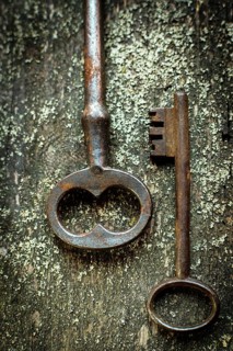 Two antique keys with intricate designs are placed on a textured wooden background. Natural light