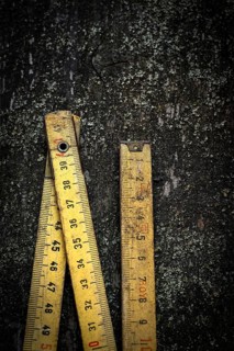Two antique wooden rulers rest on a rough, dark surface, showcasing their intricate details and