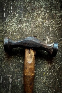 Close-up view captures the heavy hammer resting on a wooden surface, highlighting the tool's