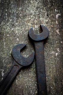 Close-up of two old, rusted wrenches on a wooden workbench, revealing their unique shapes and