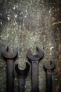 Different sizes of wrenches are arranged neatly on a weathered wooden surface, showcasing their