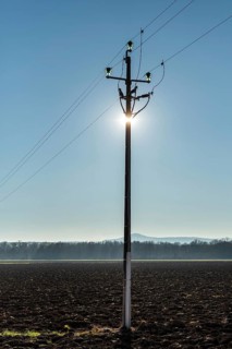 A power pole stands tall in the foreground, with sunlight shining directly behind it, creating a