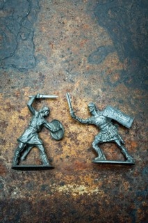 Two plast miniature figures depict a warrior with a shield and sword facing off against a roman
