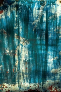 The surface displays an interplay of blue and white hues, layered textures, and hints of rust,