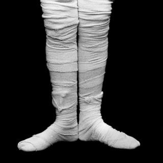 Bandaged legs are positioned closely together, highlighting medical treatment and care against a