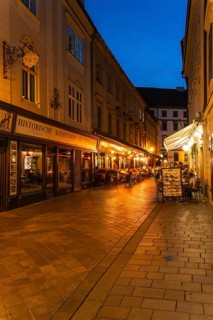 Cosy alley in the old town with illuminated cafés and historic pastry shop in Bratislava, Slovakia