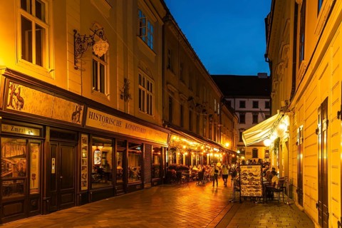 Cosy alley in the old town with illuminated cafés and historic pastry shop in Bratislava, Slovakia