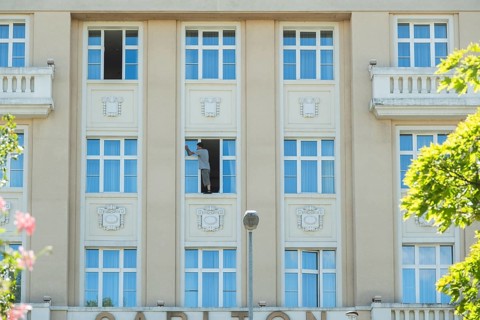 A window cleaner cleans a window and stands on the windowsill, Bratislava, Slovakia