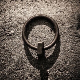 Mooring rings made of iron are embedded in the dockside, showcasing a rugged texture under soft