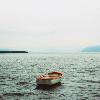 A rowing boat drifts quietly on the serene surface of Lake Geneva near Lausanne, Switzerland. The