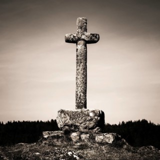 In the heart of Auvergne, a weathered stone cross rises majestically against a backdrop of