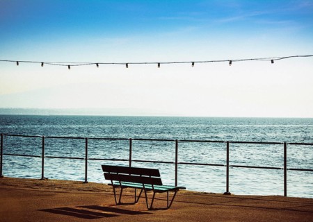 A bench is positioned along the promenade beside Geneva Lake in Nyon, Switzerland, providing a