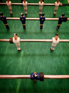 Players are set in a vintage table football game, ready for action. The colorful figures are