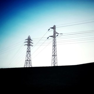Two power towers reach upwards, silhouetted against a transitioning twilight sky. The horizon is