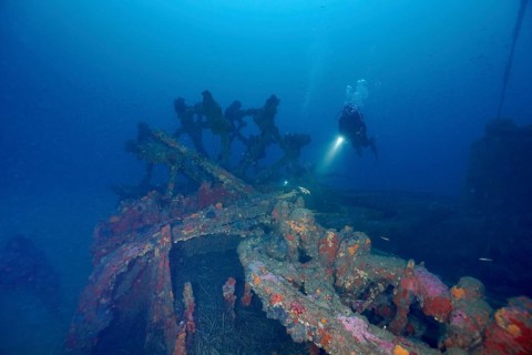 A diver explores a rusty shipwreck on the seabed. Dive site wreck Ville de Grasse, Giens peninsula,