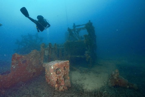 A diver examines an old shipwreck on the seabed. Dive site wreck Ville de Grasse, Giens peninsula,