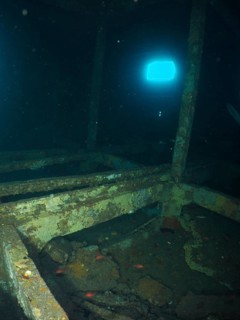 A quiet, deserted room in a shipwreck with blue light from the outside. Dive site wreck of the