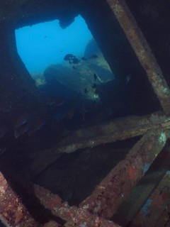View of the underwater landscape with rocks through the window of a shipwreck. Dive site wreck of