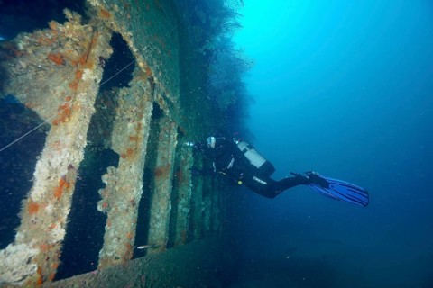 Diver exploring a derelict shipwreck in calm, clear water. Dive site wreck Le Donator, Giens