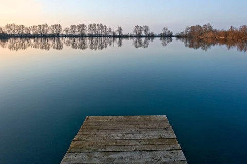 Sunset at Moosinninger Weiher with wooden footbridge, quarry pond, fishing pond for carp,