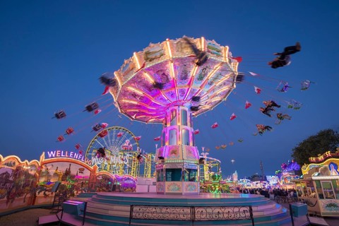 Brightly illuminated carousel at a night fair, chain carousel, spring festival, Cannstatter