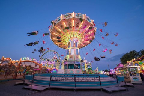 Colourful illuminated carousel turns on a funfair at night, chain carousel, spring festival,