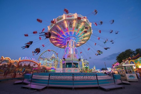 Colourful, illuminated carousel at night at a funfair, chain carousel, spring festival, Cannstatter