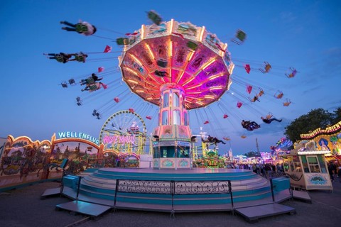 Luminous carousel turns on a colourful funfair, chain carousel, spring festival, Cannstatter