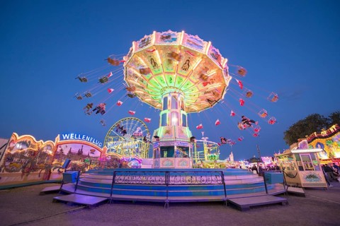 A chain carousel with lights turns at a fairground at dusk, chain carousel, spring festival,