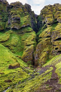 Moss-covered rock formation with entrance to the mystical lava cave, Sönghellir lava tube, Cave of