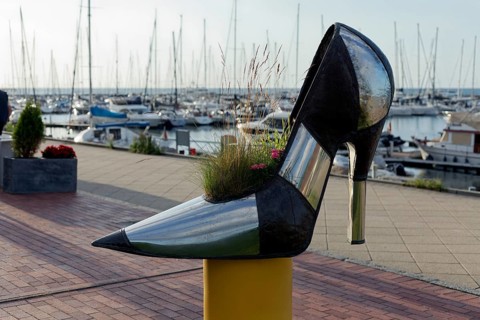 Oversized high-heeled shoe, planted with flowers, boutique on the beach promenade, Baltic resort
