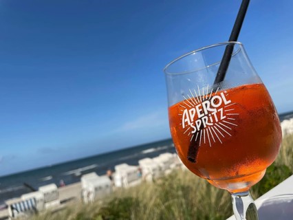 Glass of Aperol Spritz on a table overlooking the beach, Baltic resort Kühlungsborn,