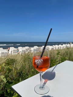 Glass of Aperol Spritz on a table overlooking the beach, Baltic resort Kühlungsborn,