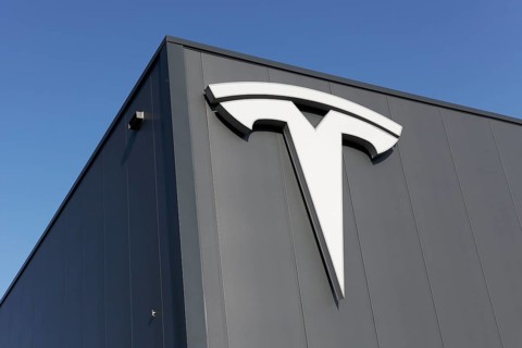 Tesla, logo on modern workshop building, figurative mark without lettering, US car manufacturer for