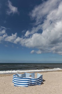 Deserted beach with person behind windbreak, blue sky, Baltic Sea near Kühlungsborn,