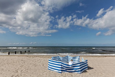 Deserted beach with person behind windbreak, blue sky, Baltic Sea near Kühlungsborn,