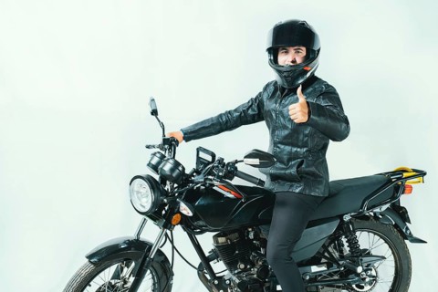 Male motorcyclist on his motorcycle with thumbs up on an isolated background. Smiling motorcyclist