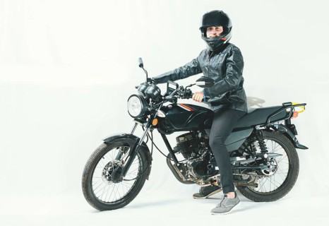 Male motorcyclist riding his motorcycle on isolated background. Smiling young man riding a