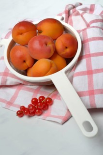 Apricots in a colander and redcurrants