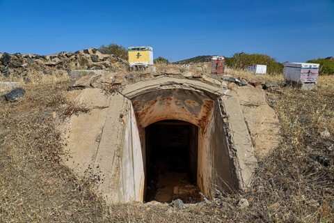 Lost Place, concrete bunker entrance in dry landscape under blue sky with vegetation, Italian air