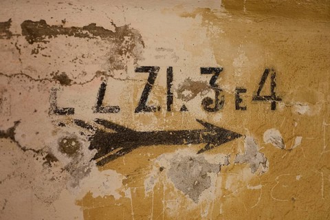 Lost Place, Ruin of a barracks, Patched wall with arrows and numbers in black on yellow, weathered