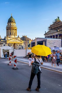 Man with a yellow umbrella standing at a barrier at Berlin's Gendarmenmarkt, Berlin, Germany