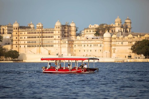 Excursion boat on Lake Pichola, behind the City Palace in the evening light, Udaipur, Rajasthan,