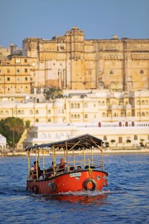 Electric excursion boat on Lake Pichola, behind the City Palace in the evening light, Udaipur,