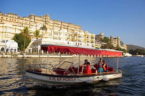 Excursion boat on Lake Pichola, behind the City Palace in the evening light, Udaipur, Rajasthan,
